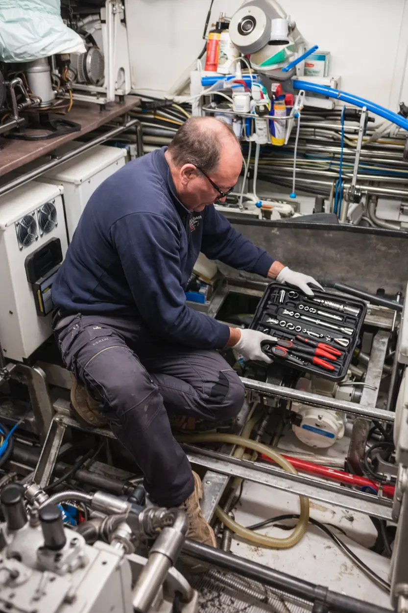 Yacht Plumbing Technician working in the engine room checking tools and onboard systems